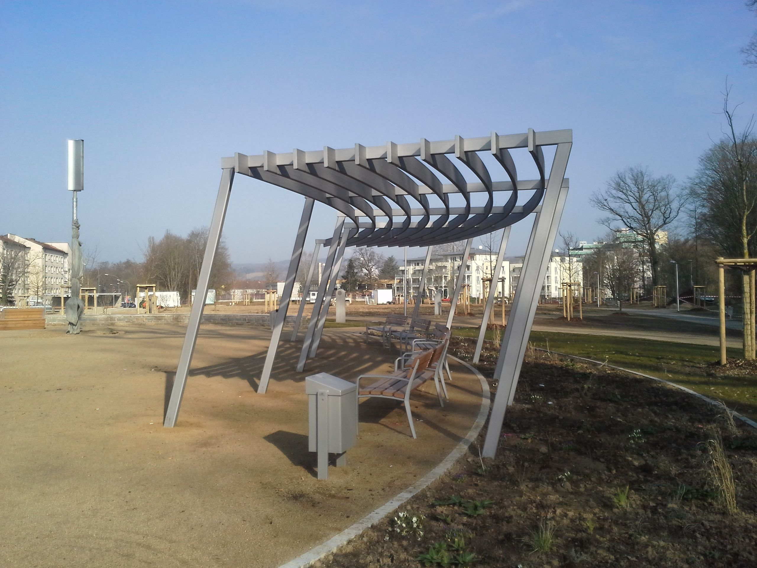 Überdachung aus grauem Metall, über Parkbänken, leicht abgerundet 
