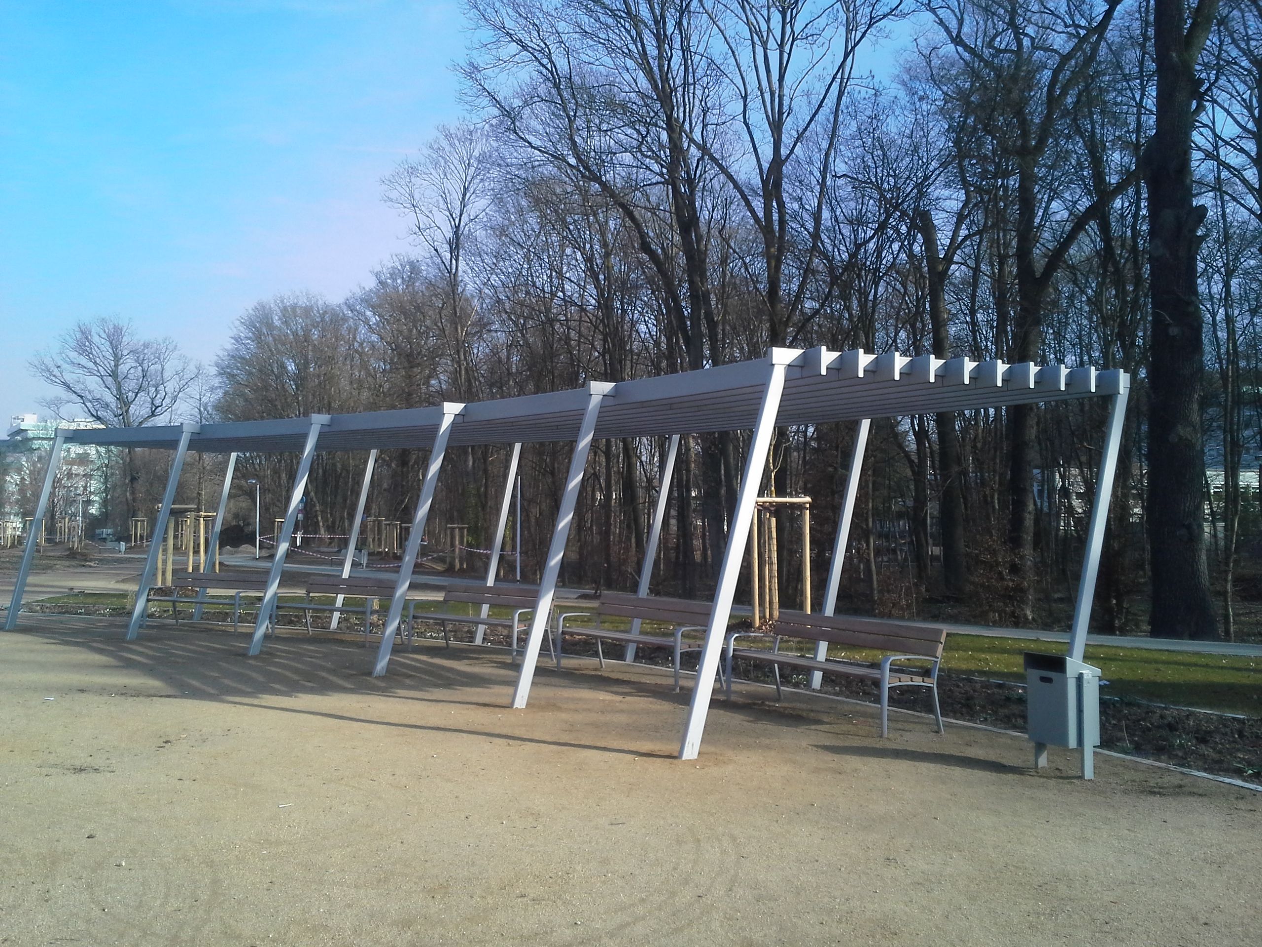 Überdachung aus grauem Metall, über Parkbänken, leicht abgerundet