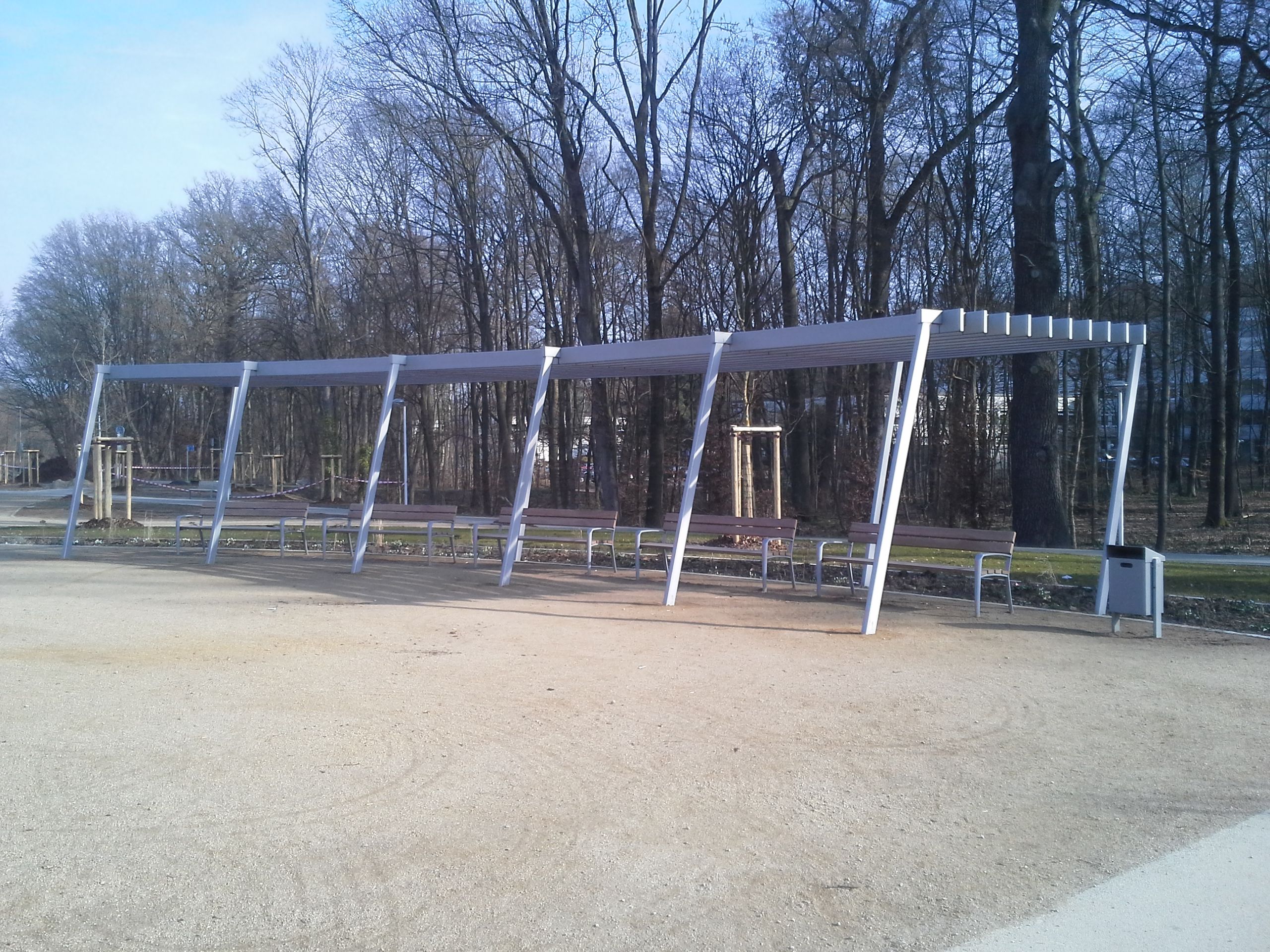 Überdachung aus grauem Metall, über Parkbänken, leicht abgerundet