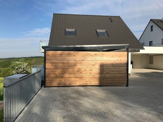 Carport mit schwarzem Metalldach und Holzplanken als Wand