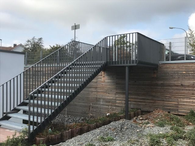 Stufen aus grauem Metallgitter mit schwarzen Metallstreben als Geländer