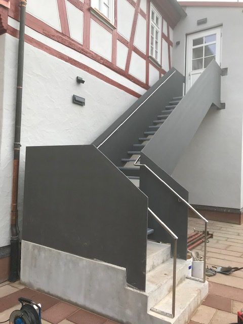 Stufen aus schwarzem Metallgitter mit Schwarzem Geländer und Steinsockel