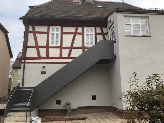 Stufen aus schwarzem Metallgitter mit Schwarzem Geländer und Steinsockel