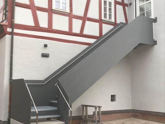 Stufen aus schwarzem Metallgitter mit Schwarzem Geländer und Steinsockel