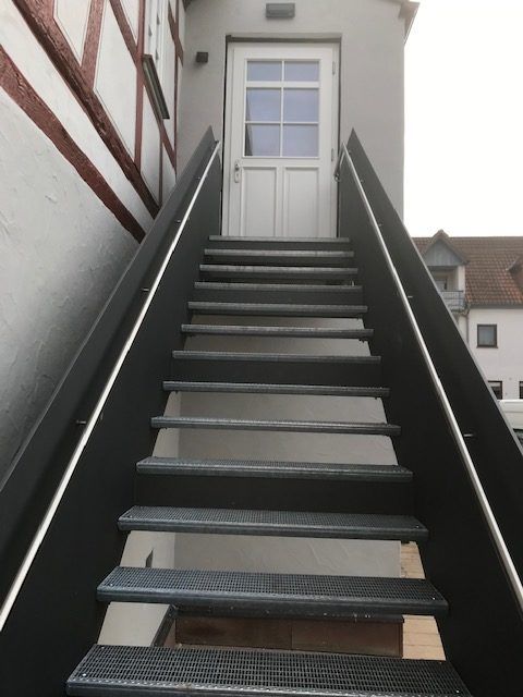 Stufen aus schwarzem Metallgitter mit Schwarzem Geländer und Steinsockel