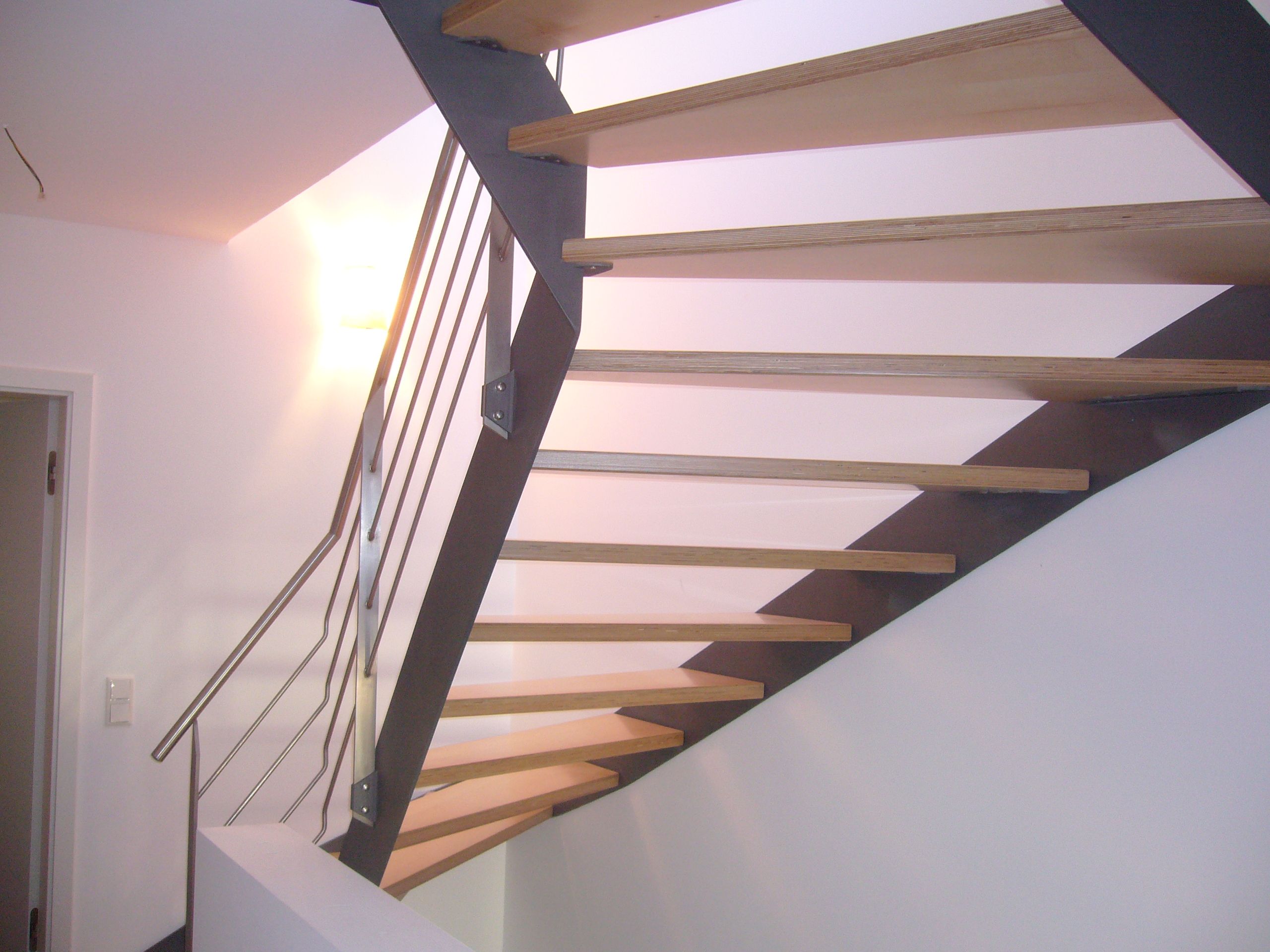 Holzstufen mit schwarzem Metallrahmen und Geländer aus grauen Metallrundstäben