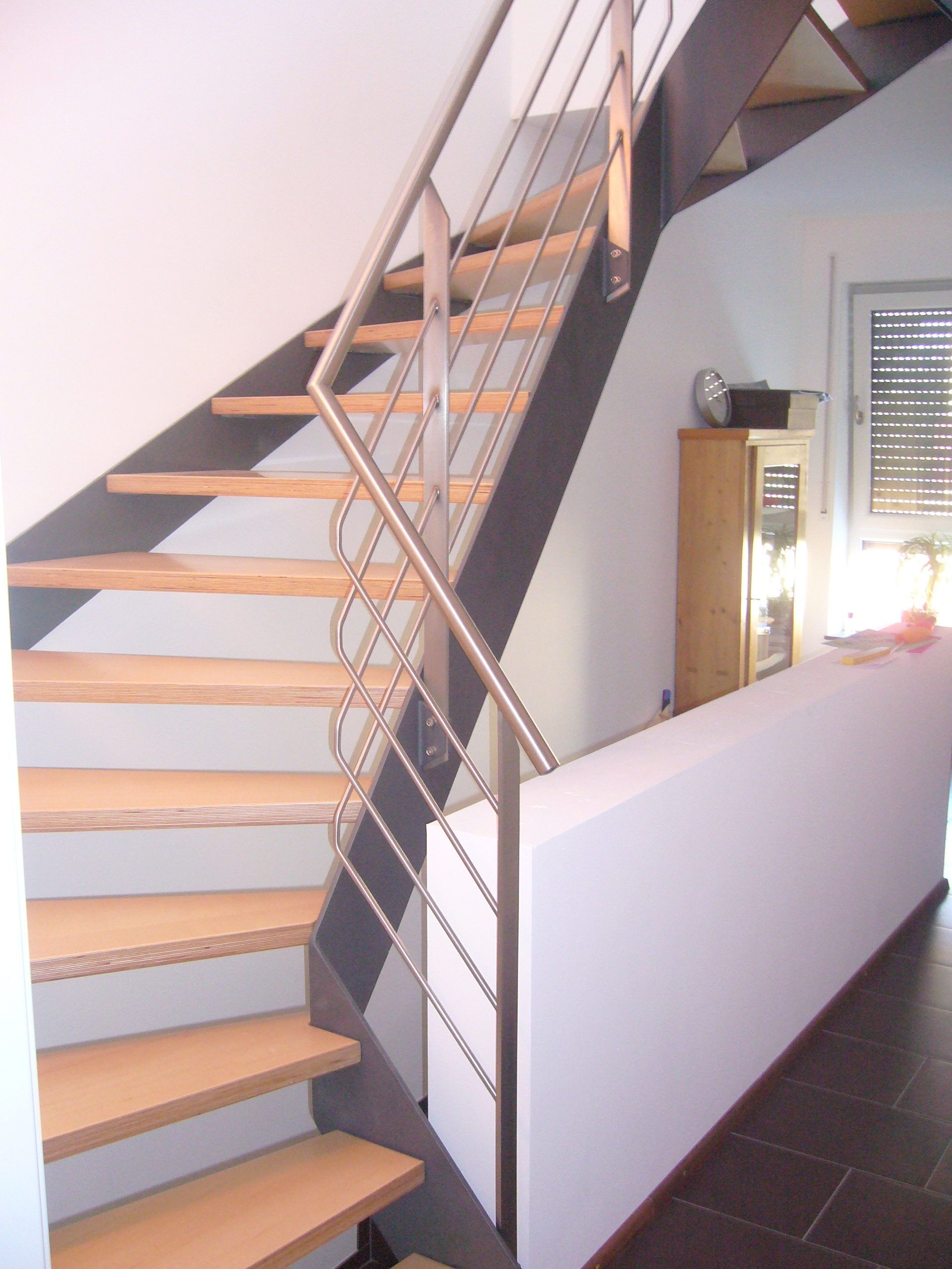 Holzstufen mit schwarzem Metallrahmen und Geländer aus grauen Metallrundstäben