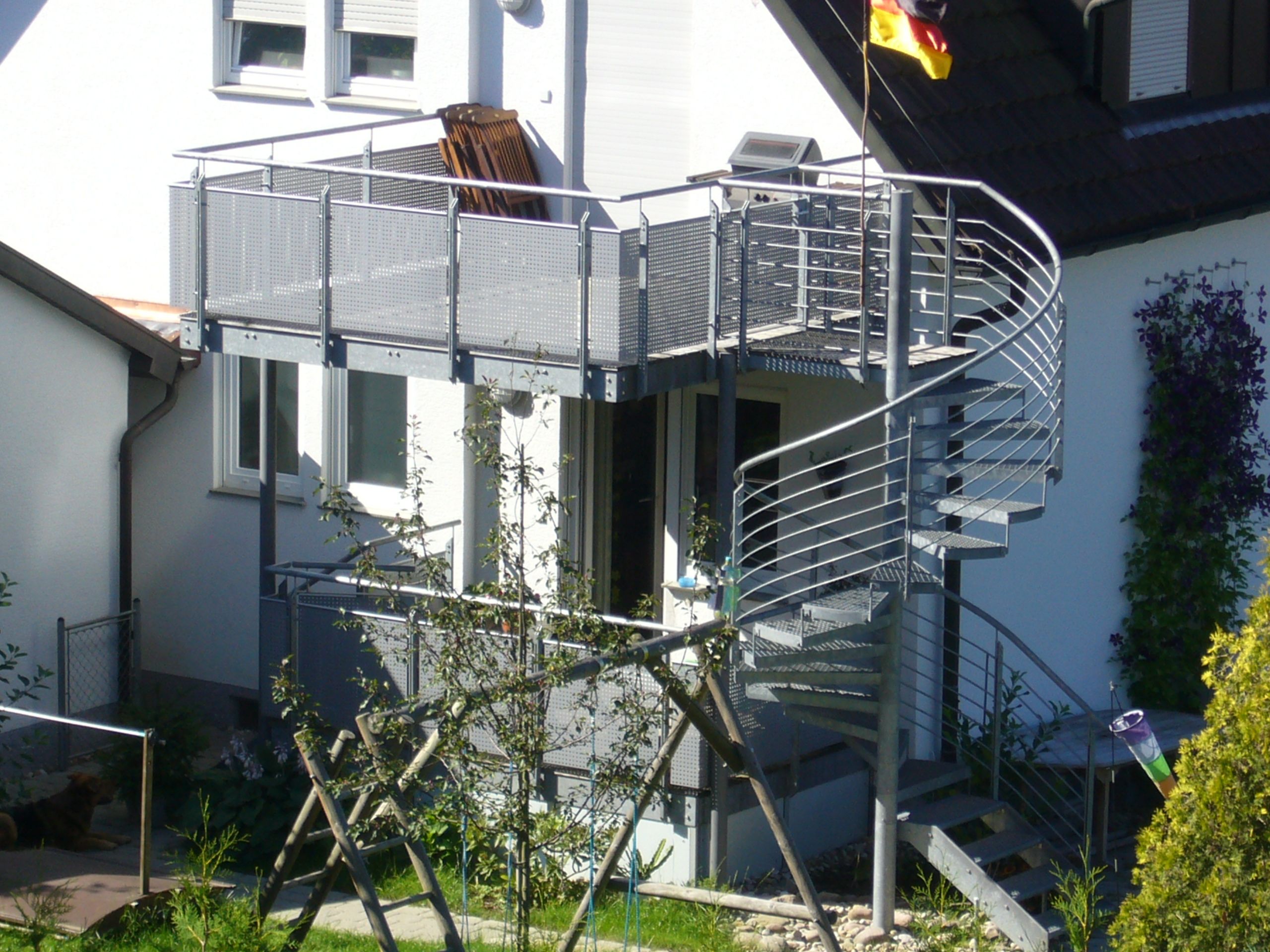 Wendeltreppe mit Stufen aus grauem Metallgitter mit einem Geländer aus Metallrundstäben