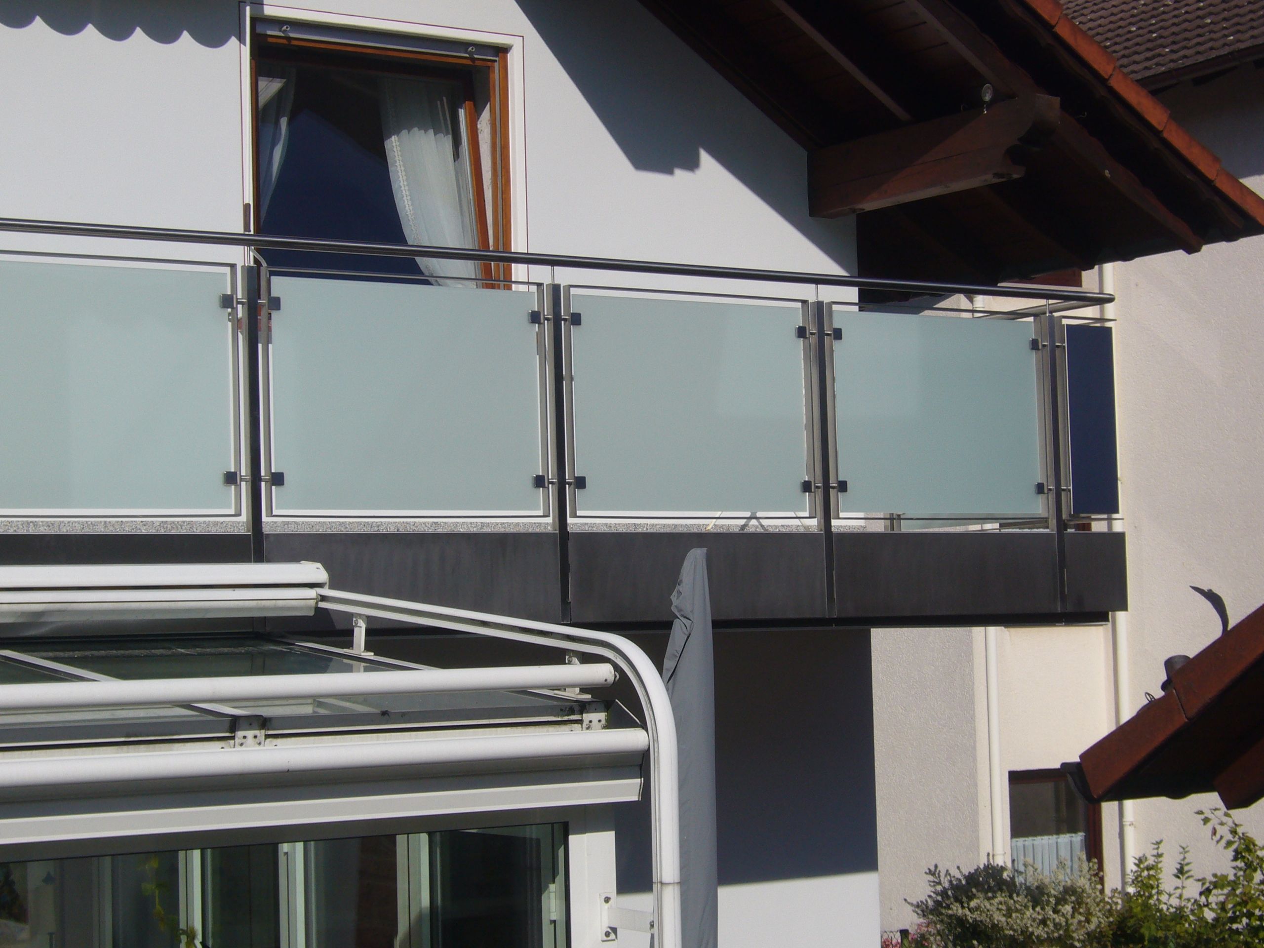 Balkongeländer aus grauen Metallstreben und Milchglas Platten 