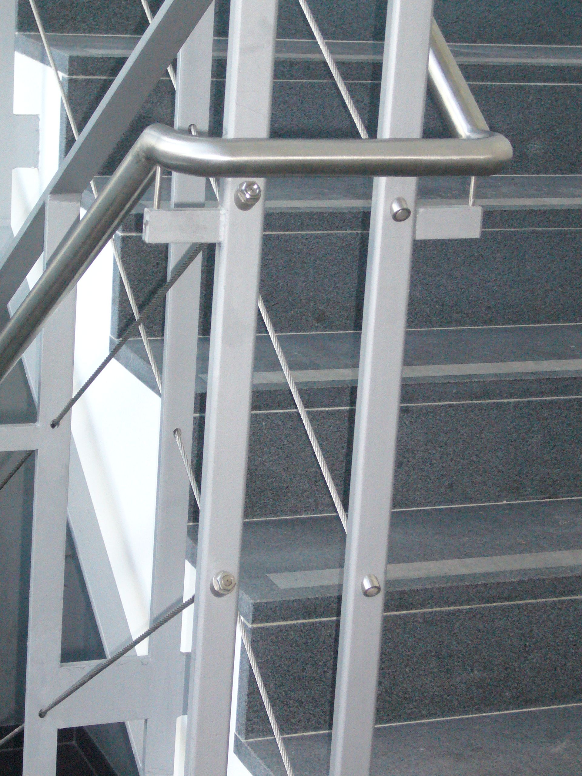 Treppengeländer aus weißen Metallstreben und grauen Metallrundstäben