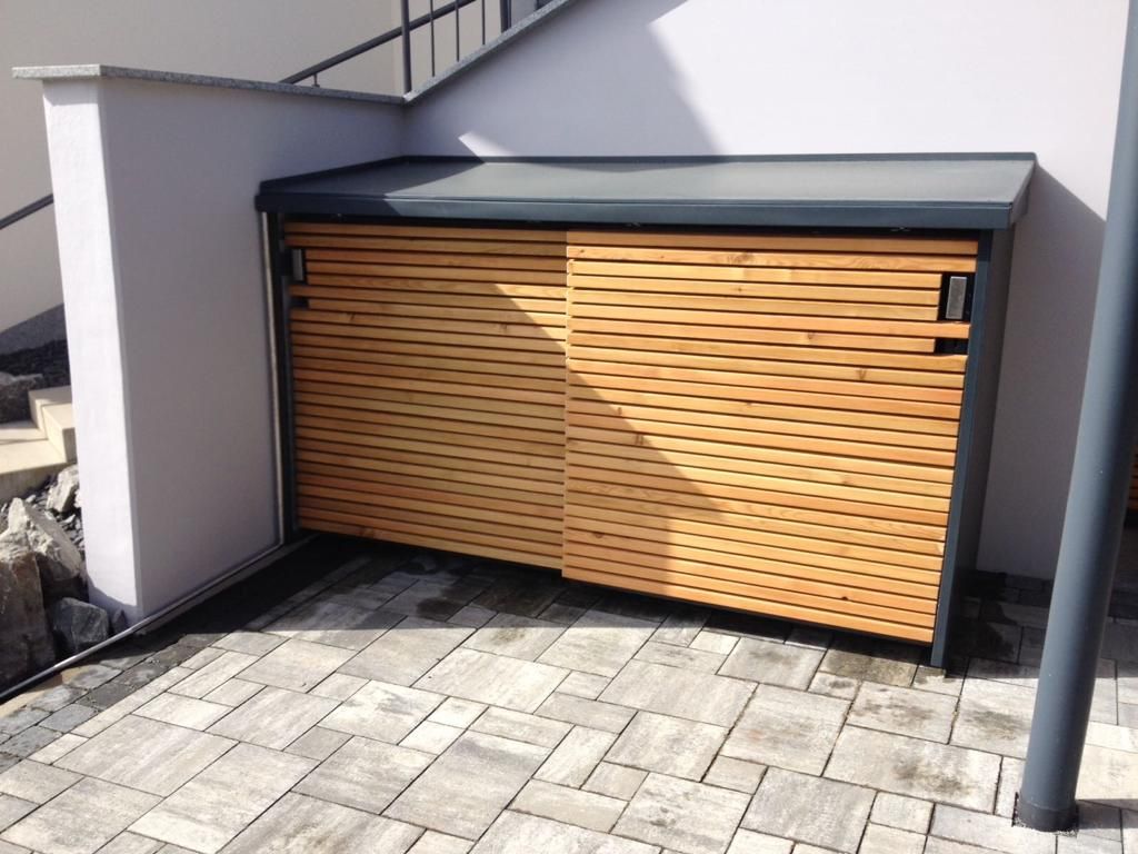 Mülltonnenverkleidung aus schwarzem Metall mit Holzplanken als Türen