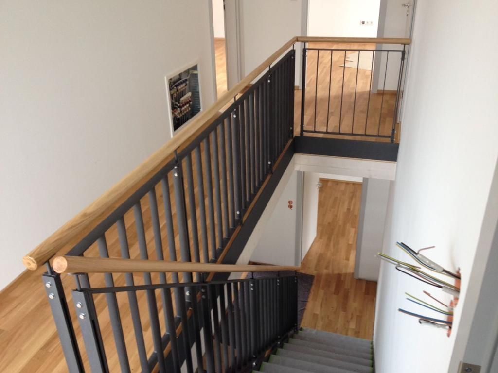 schwarze Holzstreben mit Holzhandlauf als Treppengeländer 